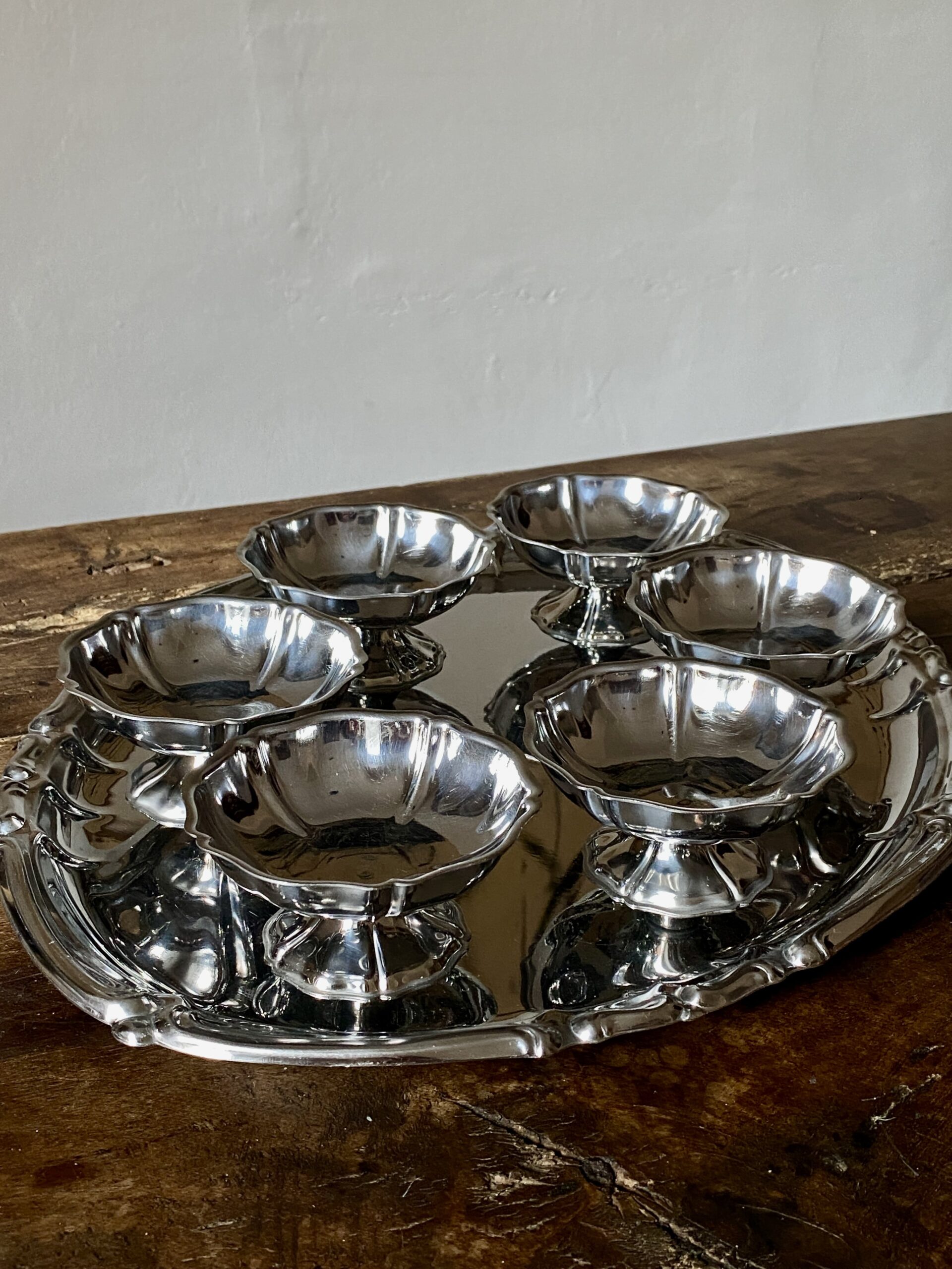 A sophisticated arrangement of slender champagne cups and sleek entertaining pieces on a vintage, reflective serving tray. The scene is set for a stylish aperitivo or evening hosting, showcasing European vintage home decor elements that bring an effortless elegance to gatherings.