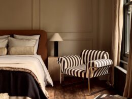 Contemporary bedroom featuring a black and white striped upholstered armchair with a tubular chrome frame, part of the 1970s striped interiors design revival in modern interior trends.