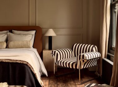 Contemporary bedroom featuring a black and white striped upholstered armchair with a tubular chrome frame, part of the 1970s striped interiors design revival in modern interior trends.